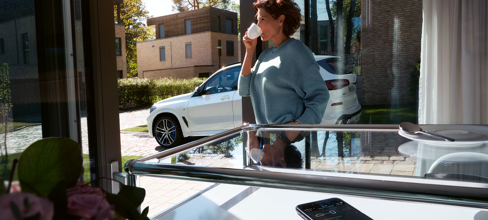 BMW Remote Software Upgrade Una donna beve da una tazza mentre BMW Remote Software Upgrade aggiorna il software della sua BMW X5