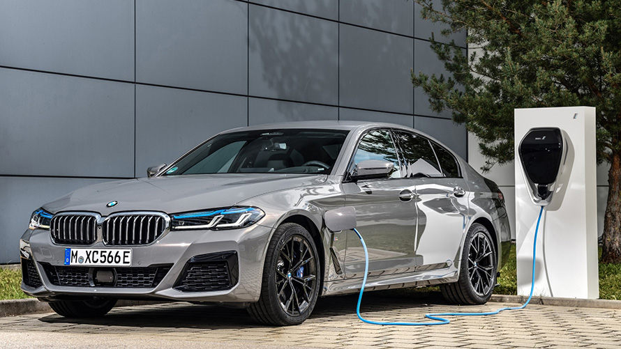 BMW Remote Software Upgrade BMW ibrida presso stazione di ricarica BMW Remote Software Upgrade BMW ibrida presso una stazione di ricarica vista anteriore a tre quarti.