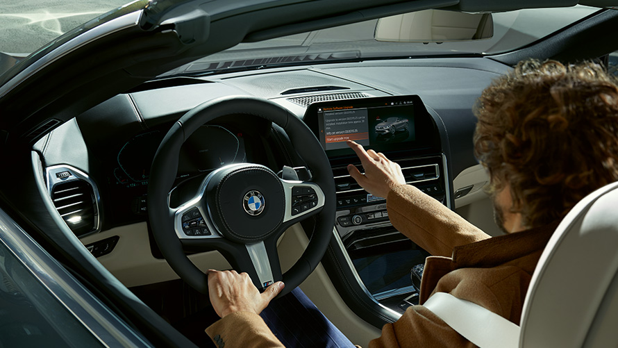Remote Software Upgrade Un uomo utilizza il Control Display seduto nella BMW Remote Software Upgrade Un uomo utilizza il Control Display seduto nella BMW