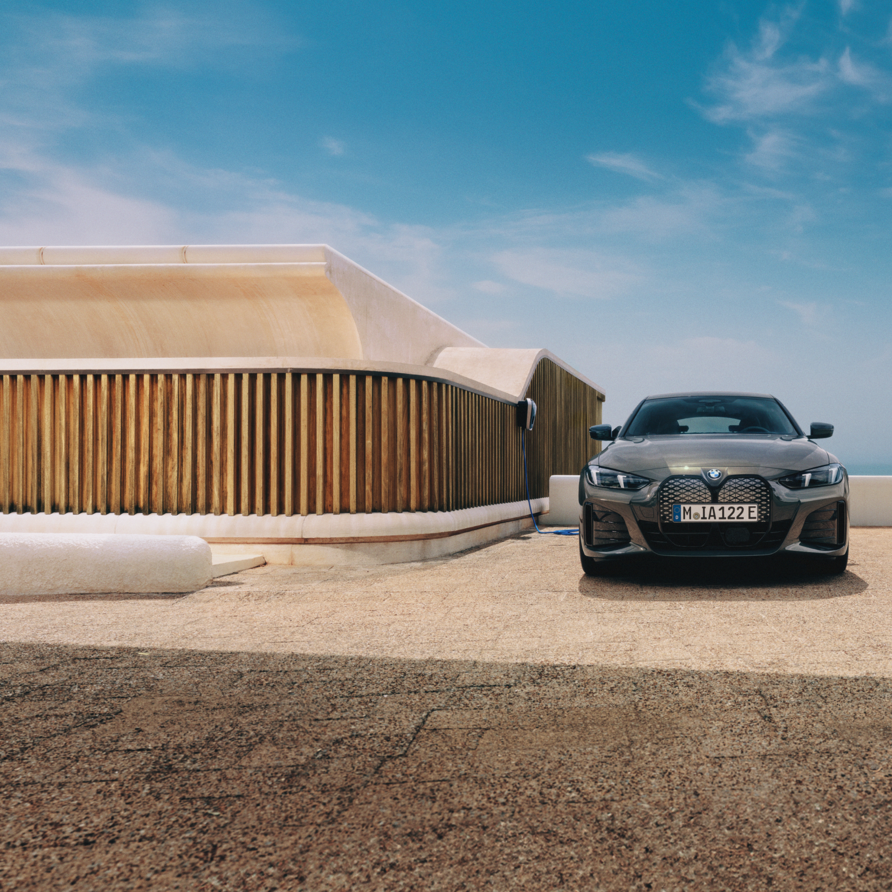 Un uomo con uno smartphone si trova accanto a una BMW i4 collegata a una Wallbox