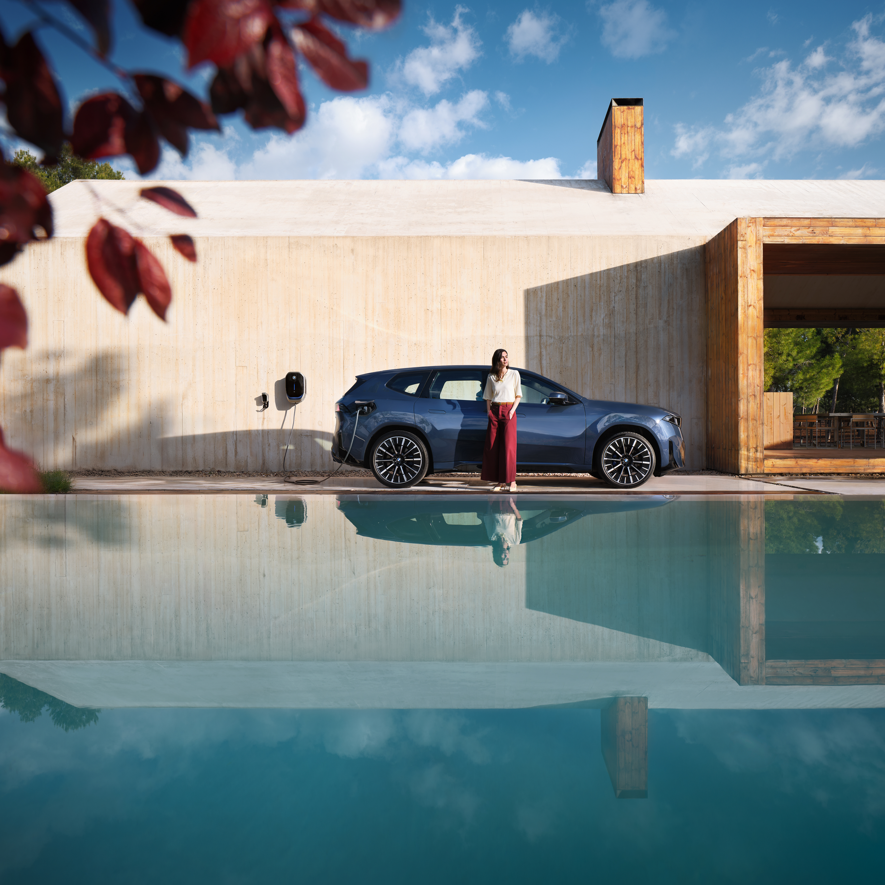 Una donna si trova davanti a una BMW iX3 collegata a una Wallbox