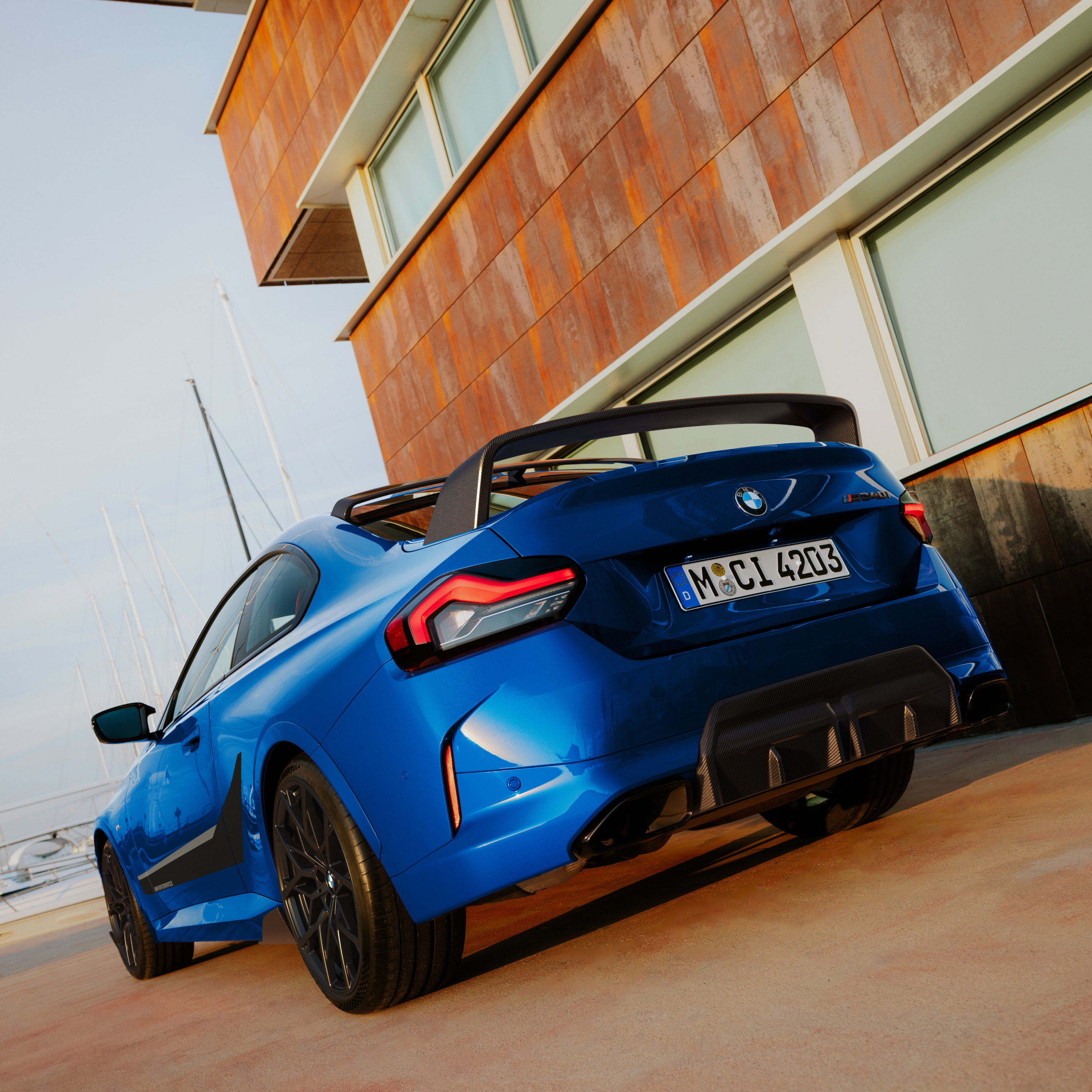 Una BMW con spoiler posteriore M Performance davanti a una casa